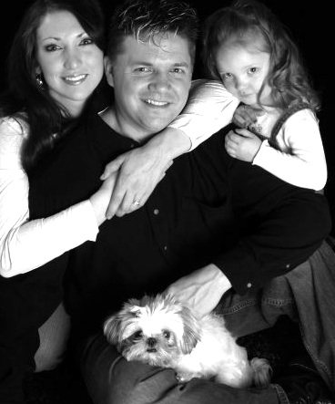 A family portrait with a young girl holding a Shih Tzu